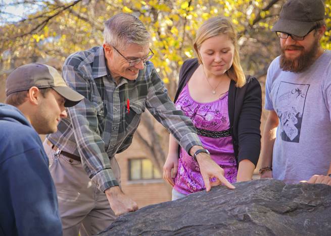 A group of people looking at a rock

Description automatically generated